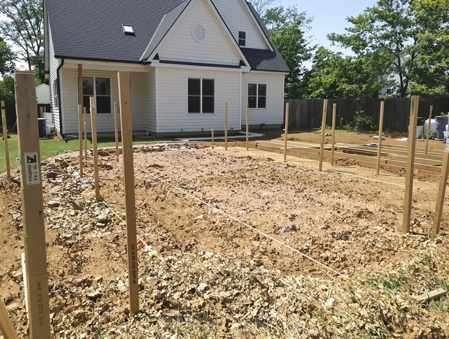 A California backyard with survey stakes marking where an ADU will be built