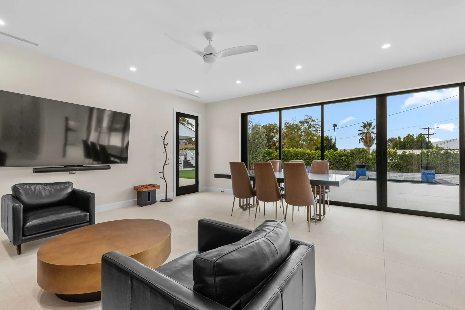 ADU living room with black leather seating, dining table and floor-to-ceiling sliders to the pool
