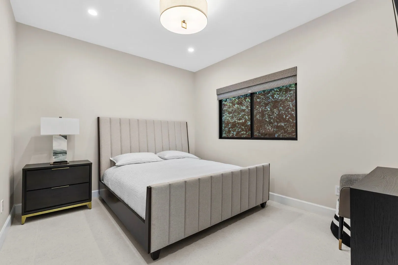 ADU bedroom with channel-tufted upholstered bed, dark wood nightstand and warm lighting