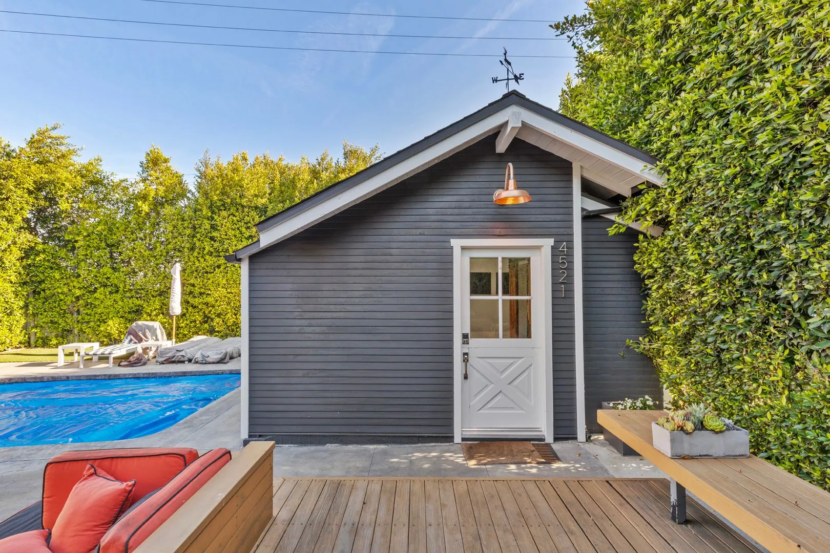 Modern detached ADU in Los Angeles with poolside deck, dark navy siding and outdoor lounge