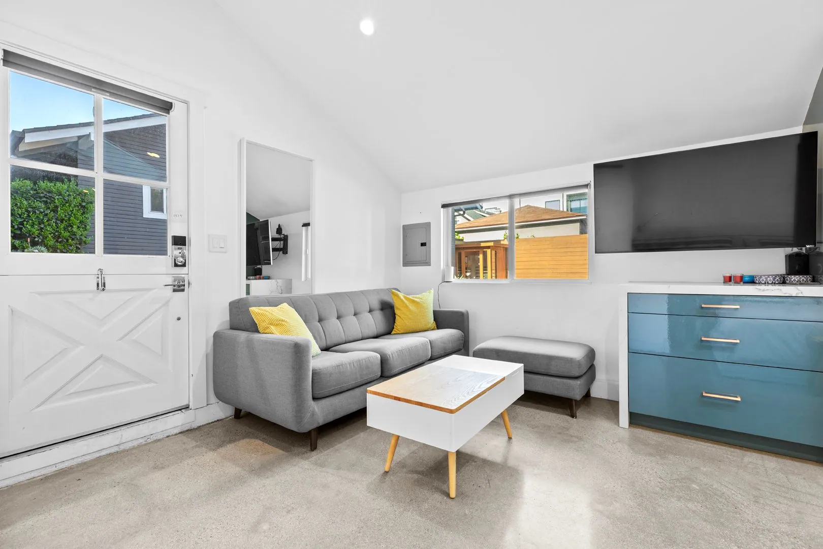 ADU living room with vaulted ceiling, gray sofa and yellow accent pillows