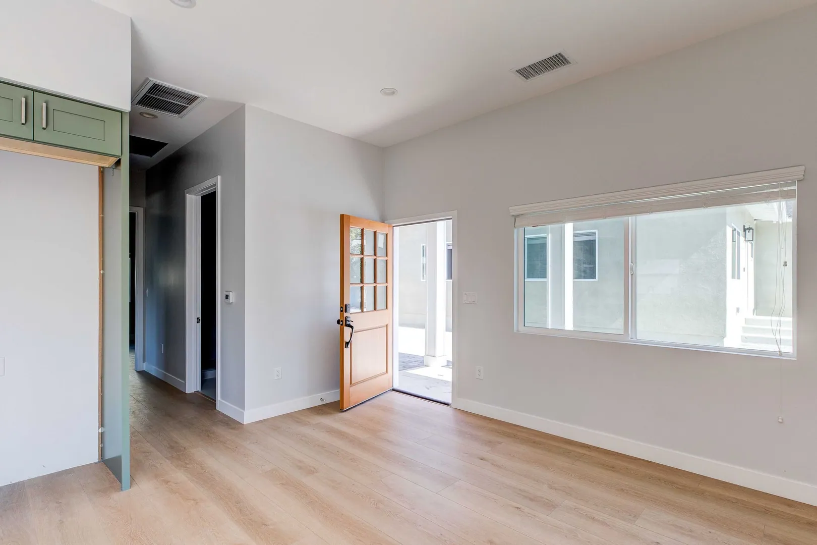 ADU living area with light oak floors, vaulted ceiling and Dutch entry door